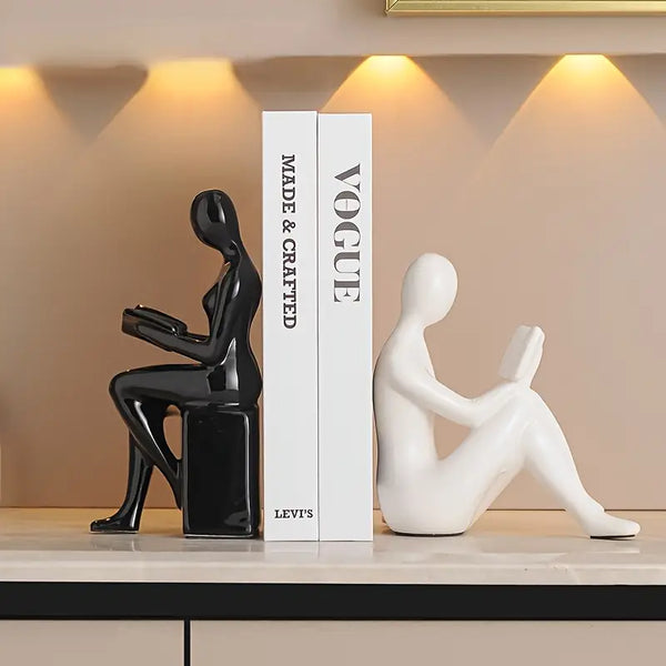 Two abstract sculpture figures on a shelf with a 'Vogue' book in the  decor aura works