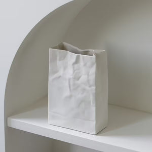 White textured vase on a white shelf against a neutral wall