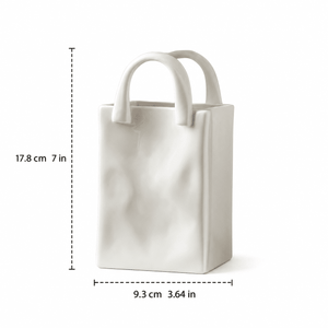A white ceramic vase shaped like a tote bag with dashed measurement lines showing dimensions of 17.8 cm (7 in) in height and 9.