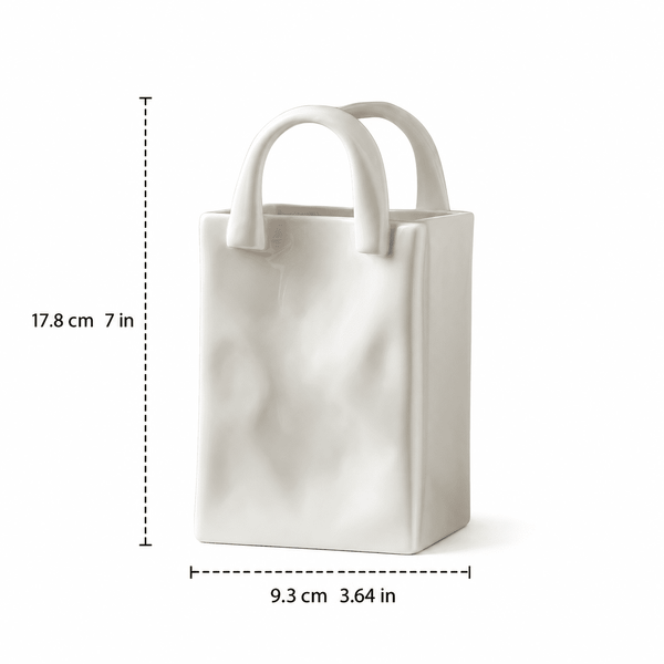 A white ceramic vase shaped like a tote bag with dashed measurement lines showing dimensions of 17.8 cm (7 in) in height and 9.