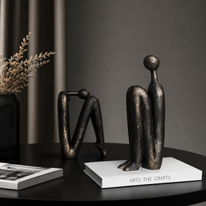 Two bronze sculptures on a dark surface with a book titled 'Arts The Crafts' in the background.