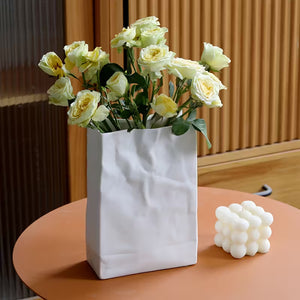 White vase with yellow flowers on a wooden table