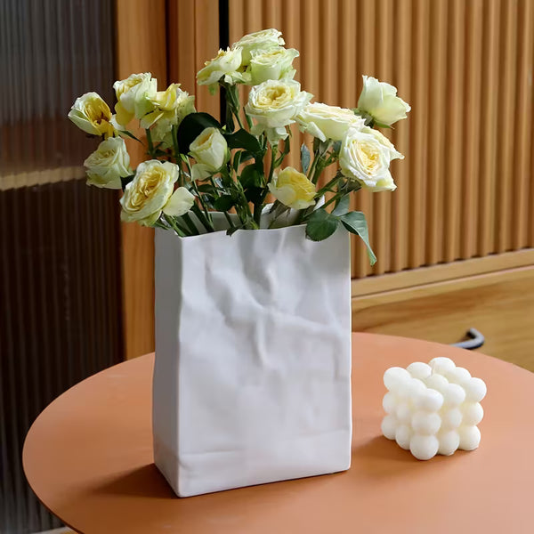 White vase with yellow flowers on a wooden table
