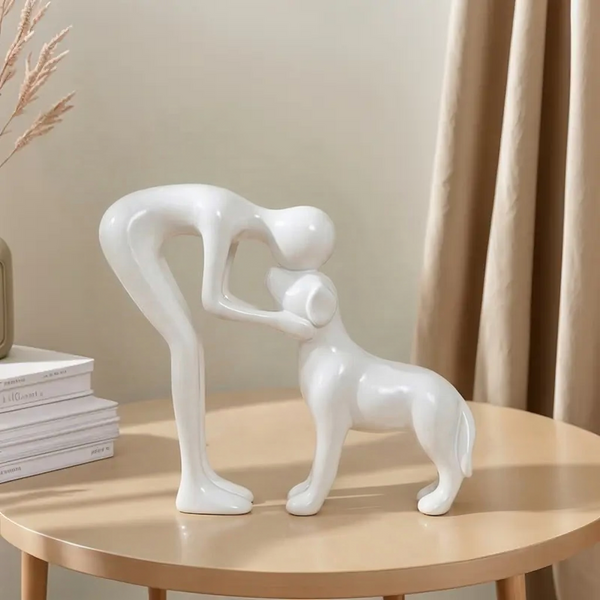 White ceramic sculpture of a woman and a dog on a wooden table with a neutral background