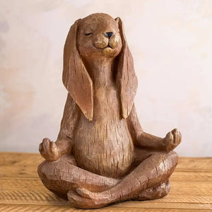 Wooden sculpture of a dog in a meditative pose on a wooden surface with a neutral background
