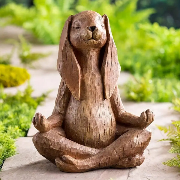 Wooden sculpture of a dog in a meditative pose on a stone path with greenery in the background
